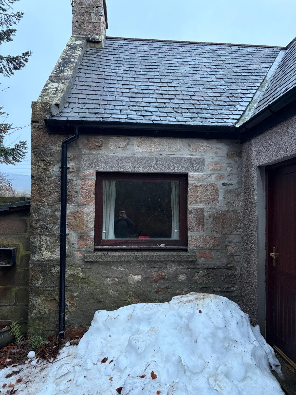 Traditional slate roof beside a stone gable and chimney